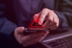 10DLC Regulations - Red triangle exclamation point alert over someone typing on their phone